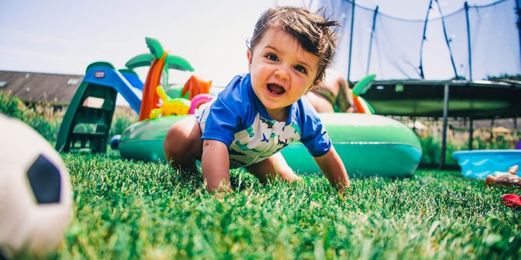 boy in blue and white crew neck t-shirt sitting on green grass field during daytime